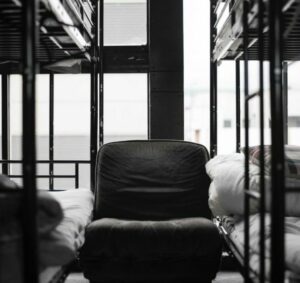 Photo by Taiga Ishii . A chair in between bunk beds at a dormitory. 